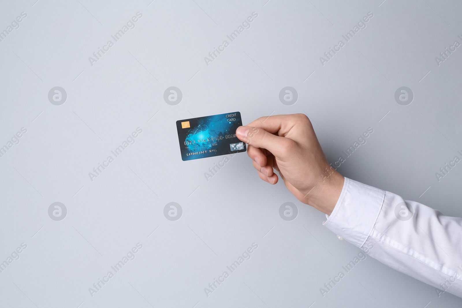 Photo of Man holding credit card on light grey background, closeup