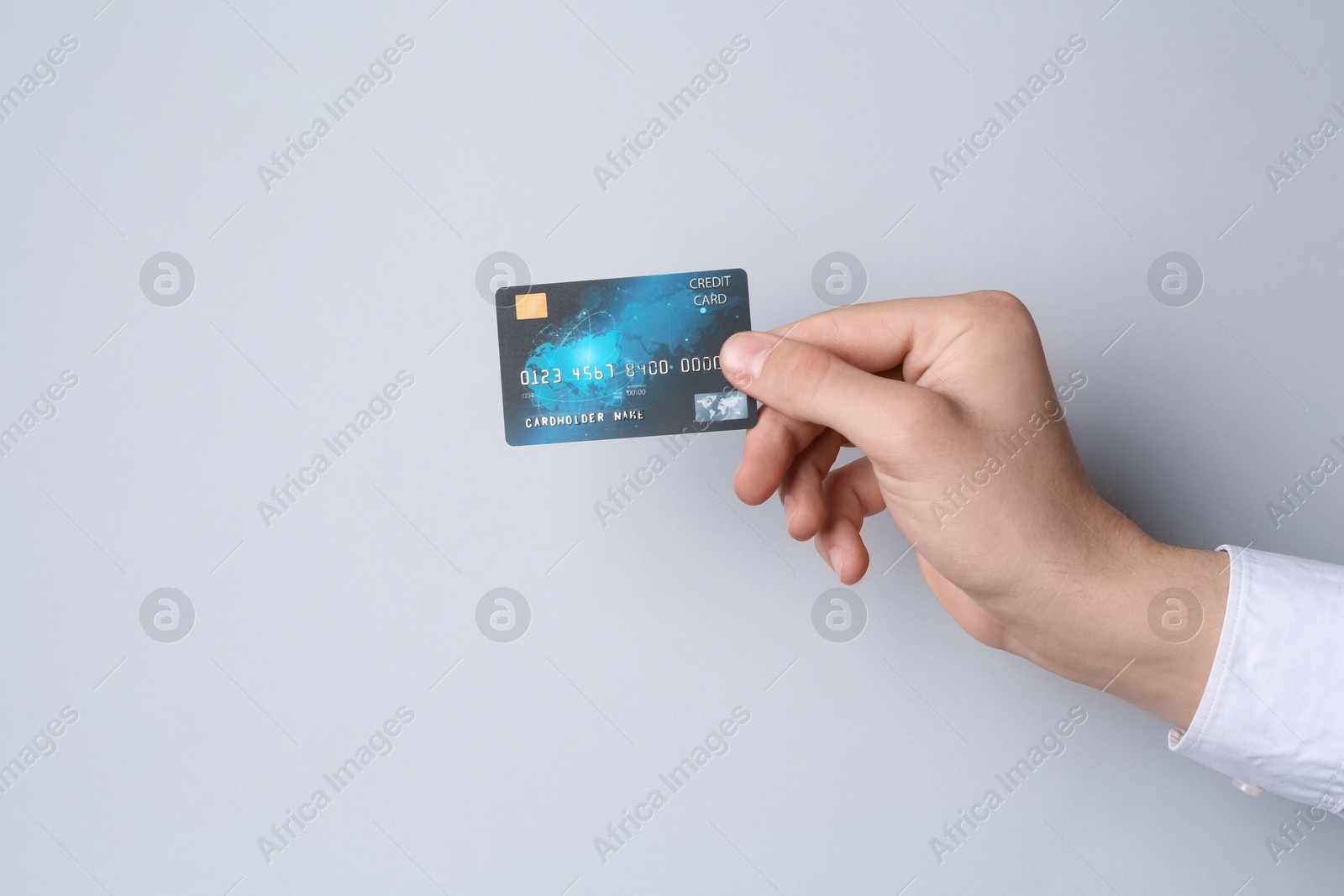 Photo of Man holding credit card on light grey background, closeup