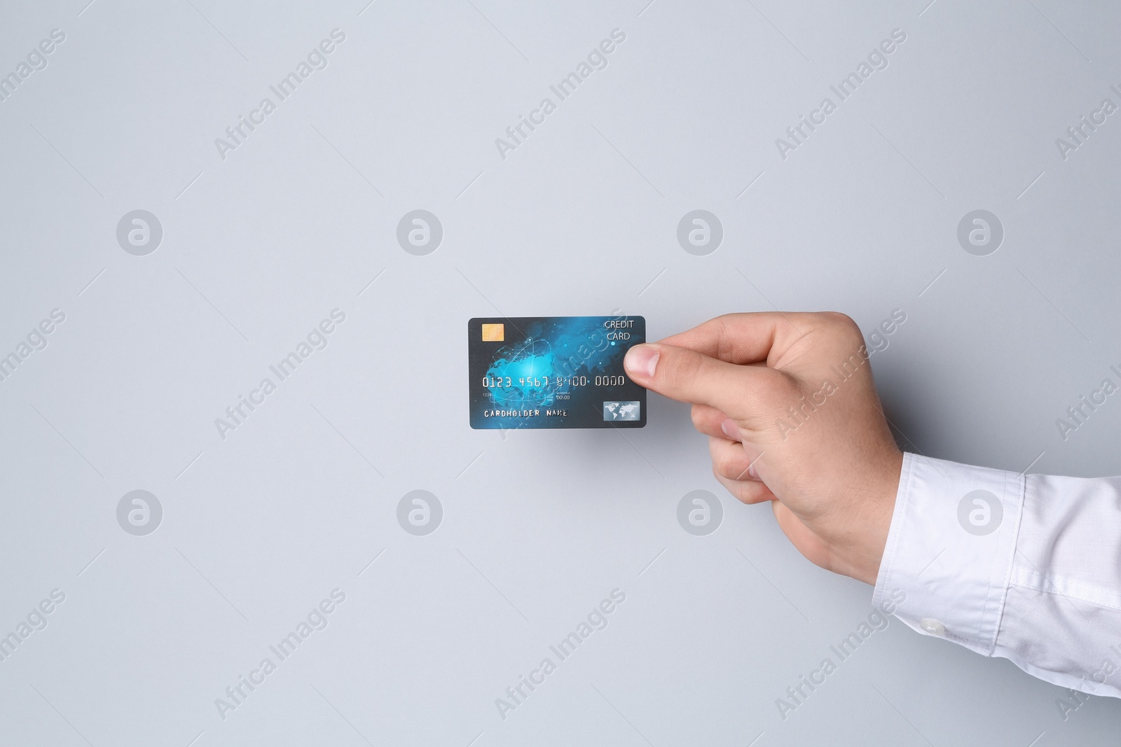 Photo of Man holding credit card on light grey background, closeup