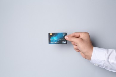 Man holding credit card on light grey background, closeup