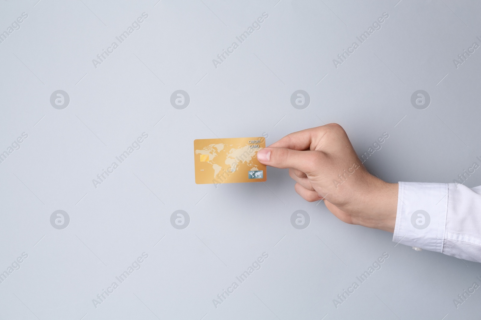 Photo of Man holding credit card on light grey background, closeup