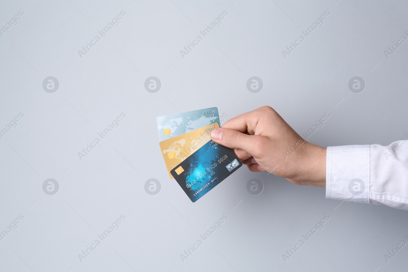 Photo of Man holding credit cards on light grey background, closeup