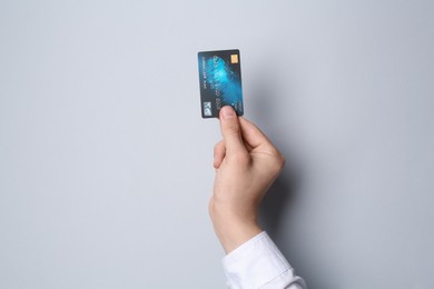 Man holding credit card on light grey background, closeup