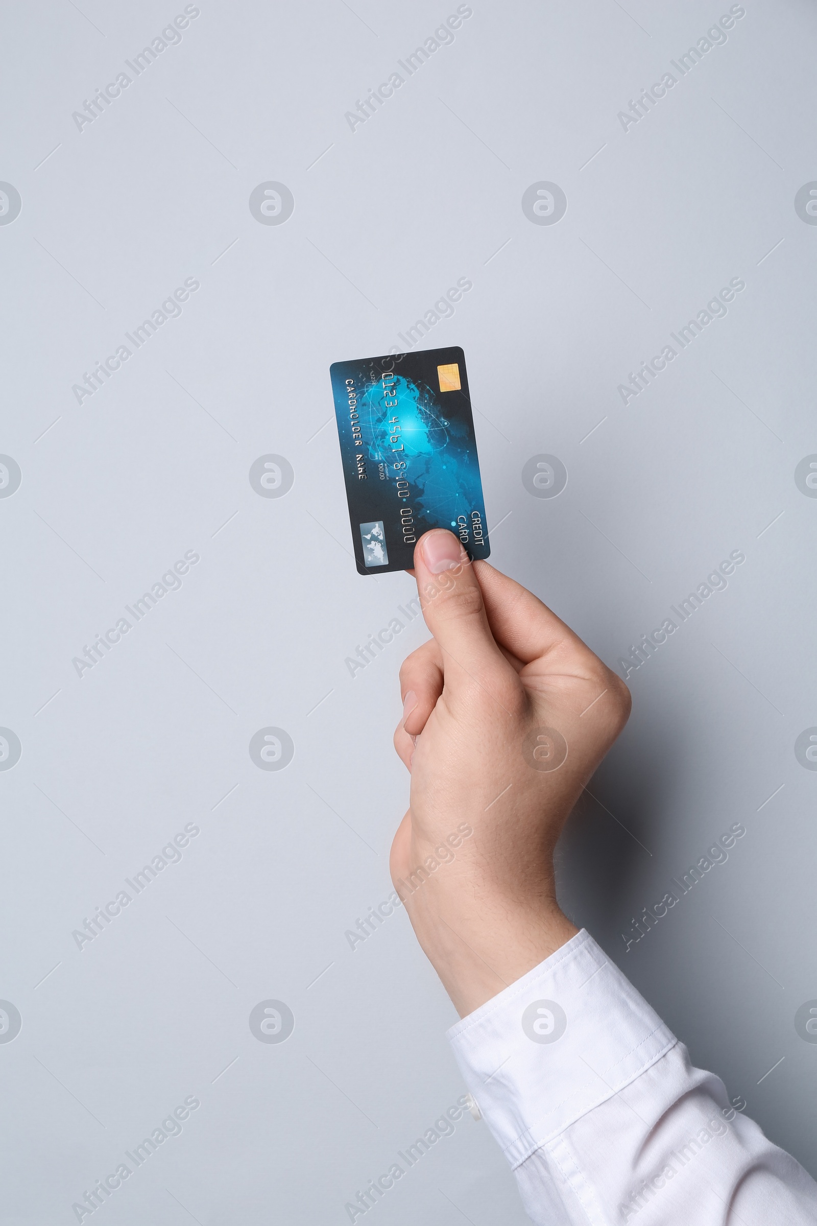 Photo of Man holding credit card on light grey background, closeup