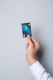 Man holding credit card on light grey background, closeup