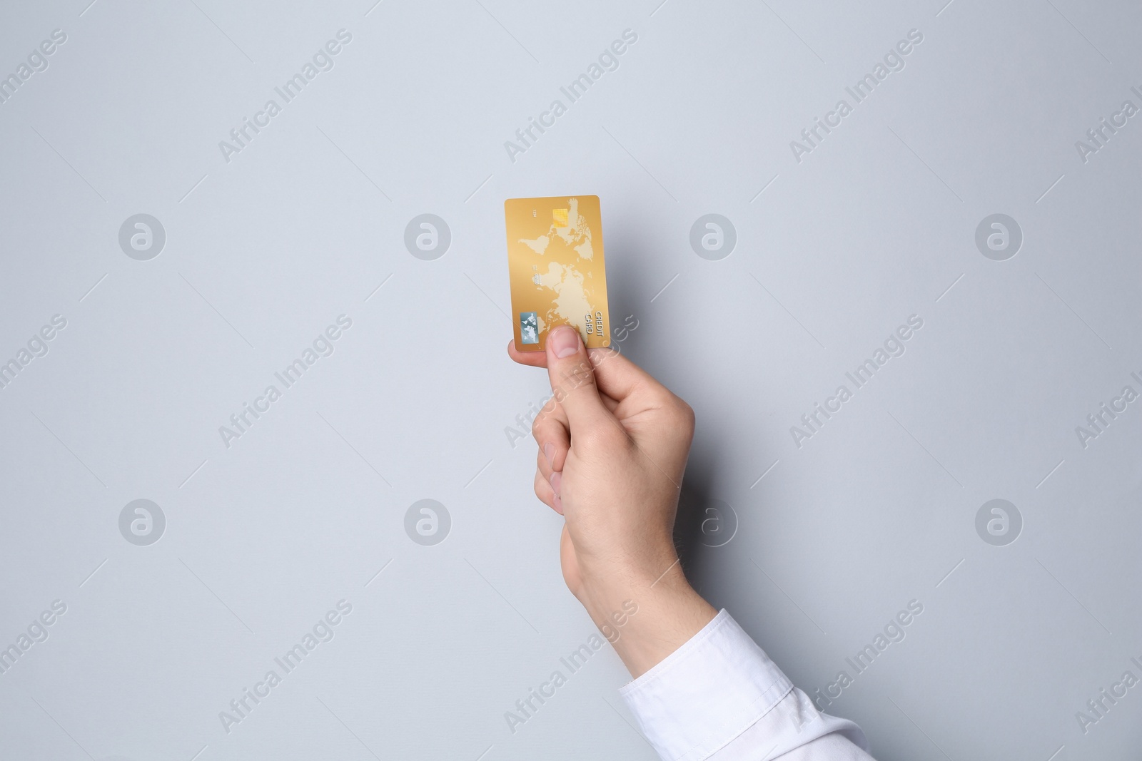 Photo of Man holding credit card on light grey background, closeup