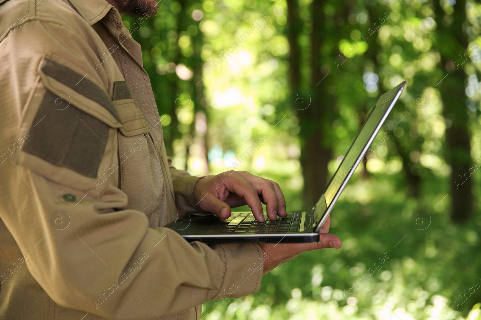 Photo of Forester with laptop examining plants in forest, closeup