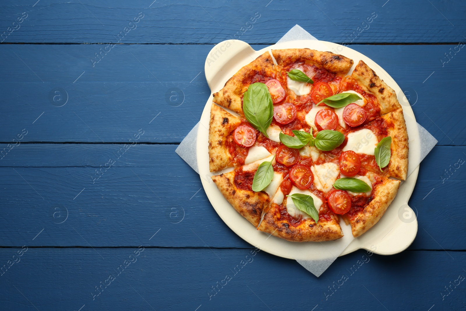 Photo of Delicious Margherita pizza on blue wooden table, top view. Space for text