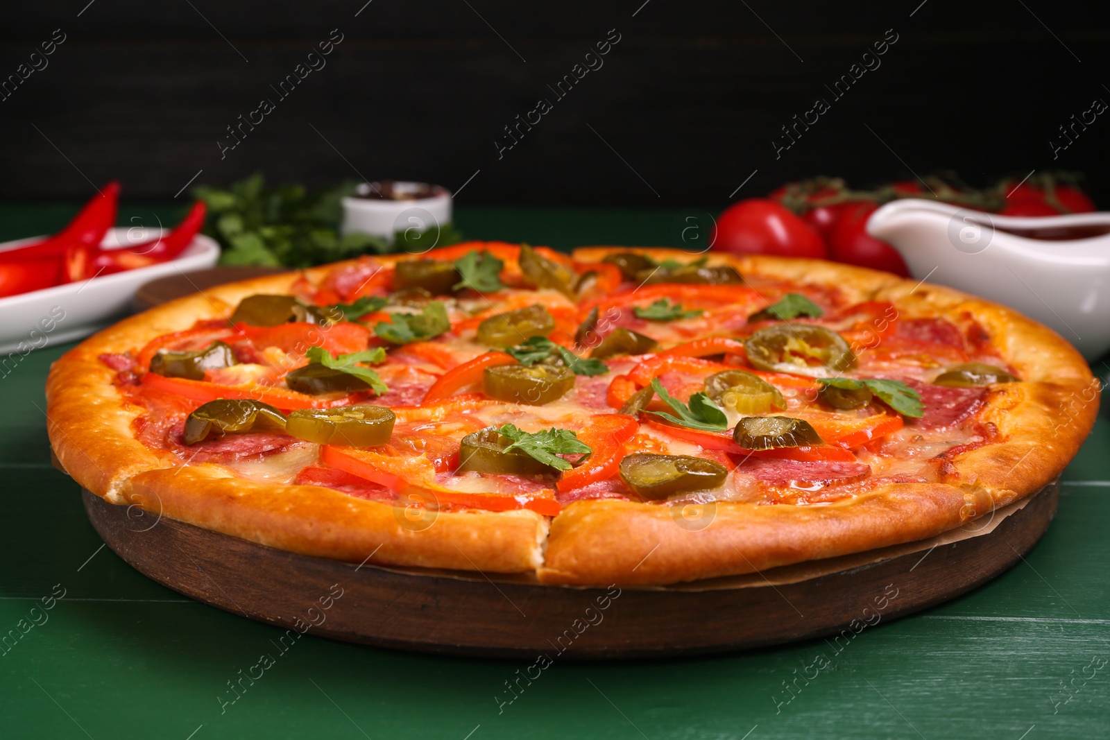 Photo of Delicious pizza Diablo on green wooden table, closeup