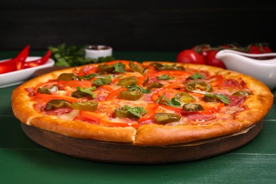 Delicious pizza Diablo on green wooden table, closeup