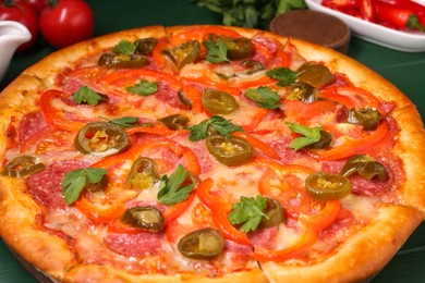 Photo of Delicious pizza Diablo on green wooden table, closeup