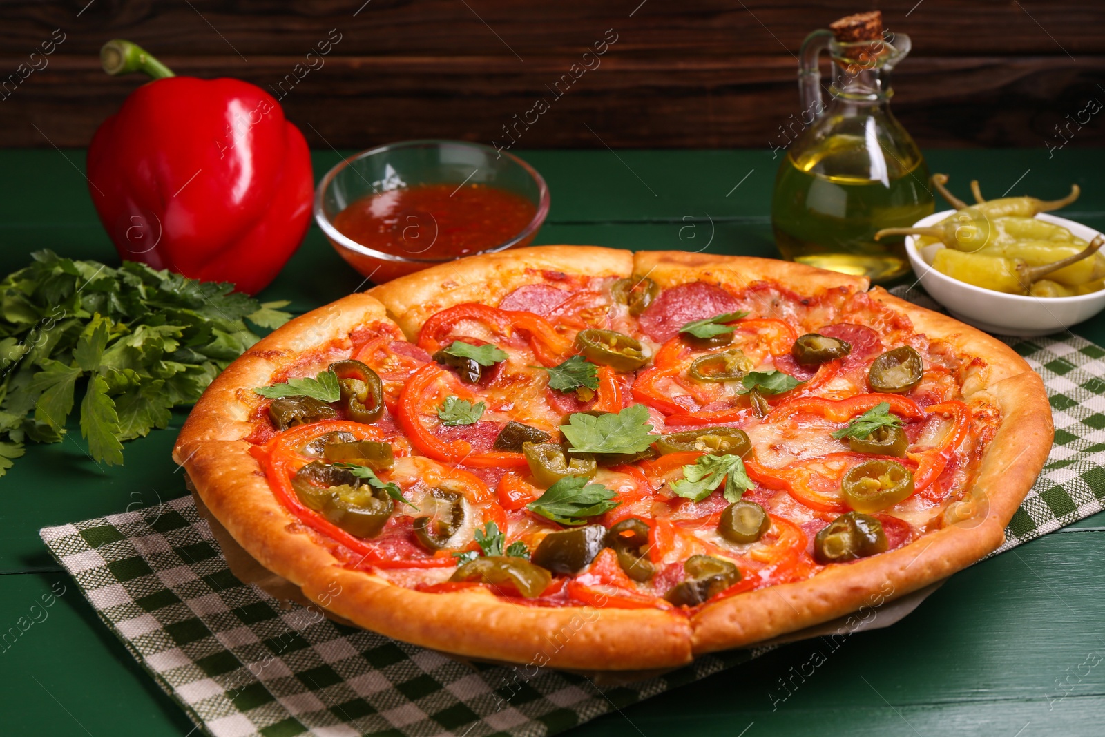 Photo of Delicious pizza Diablo and ingredients on green wooden table