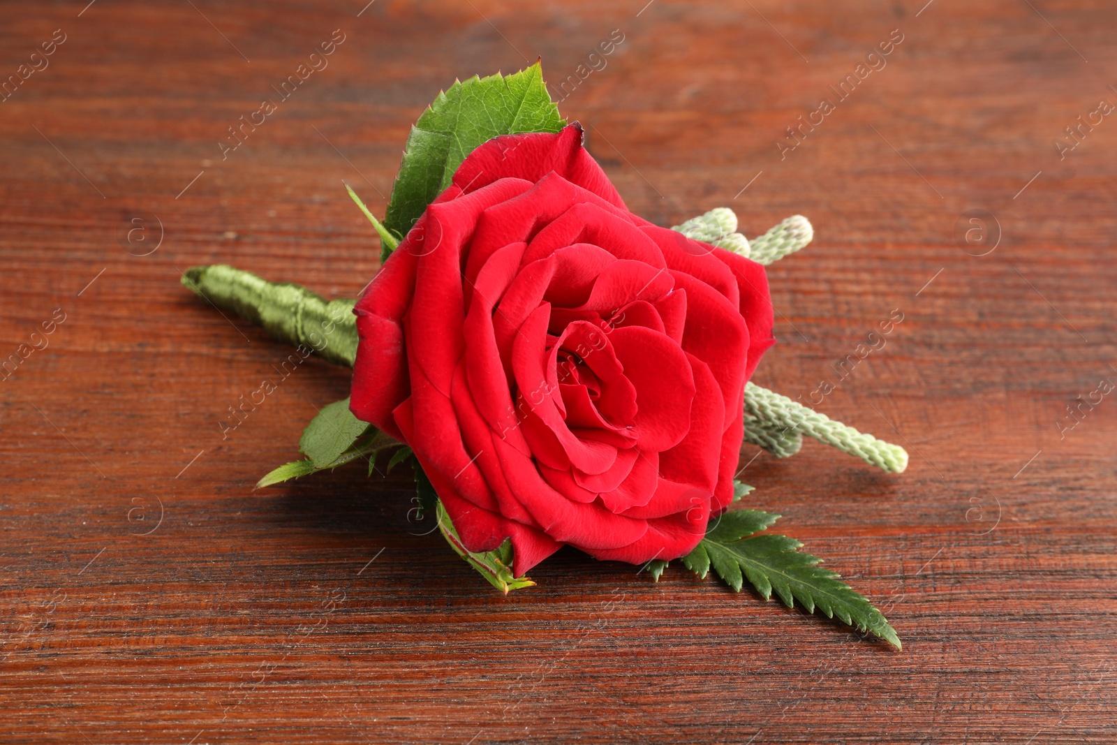 Photo of One stylish red boutonniere on wooden table