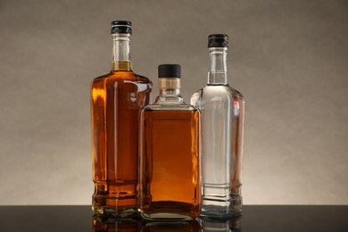 Photo of Bottles of different alcoholic drinks on table against gray background