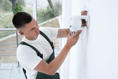 Technician installing CCTV camera on wall indoors