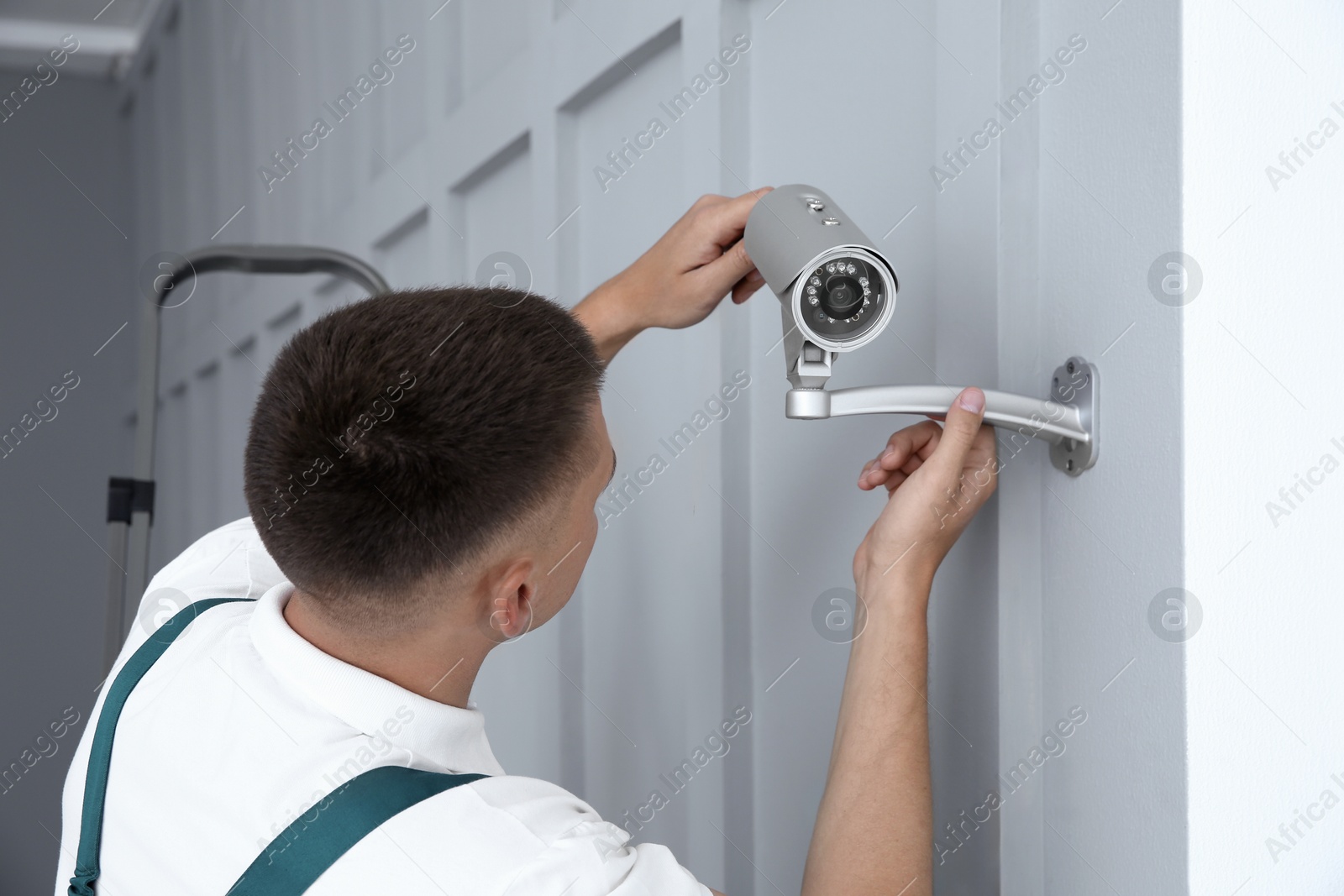 Photo of Technician installing CCTV camera on wall indoors