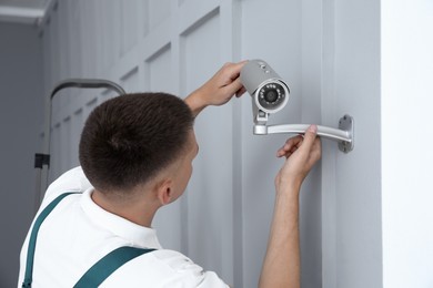 Technician installing CCTV camera on wall indoors