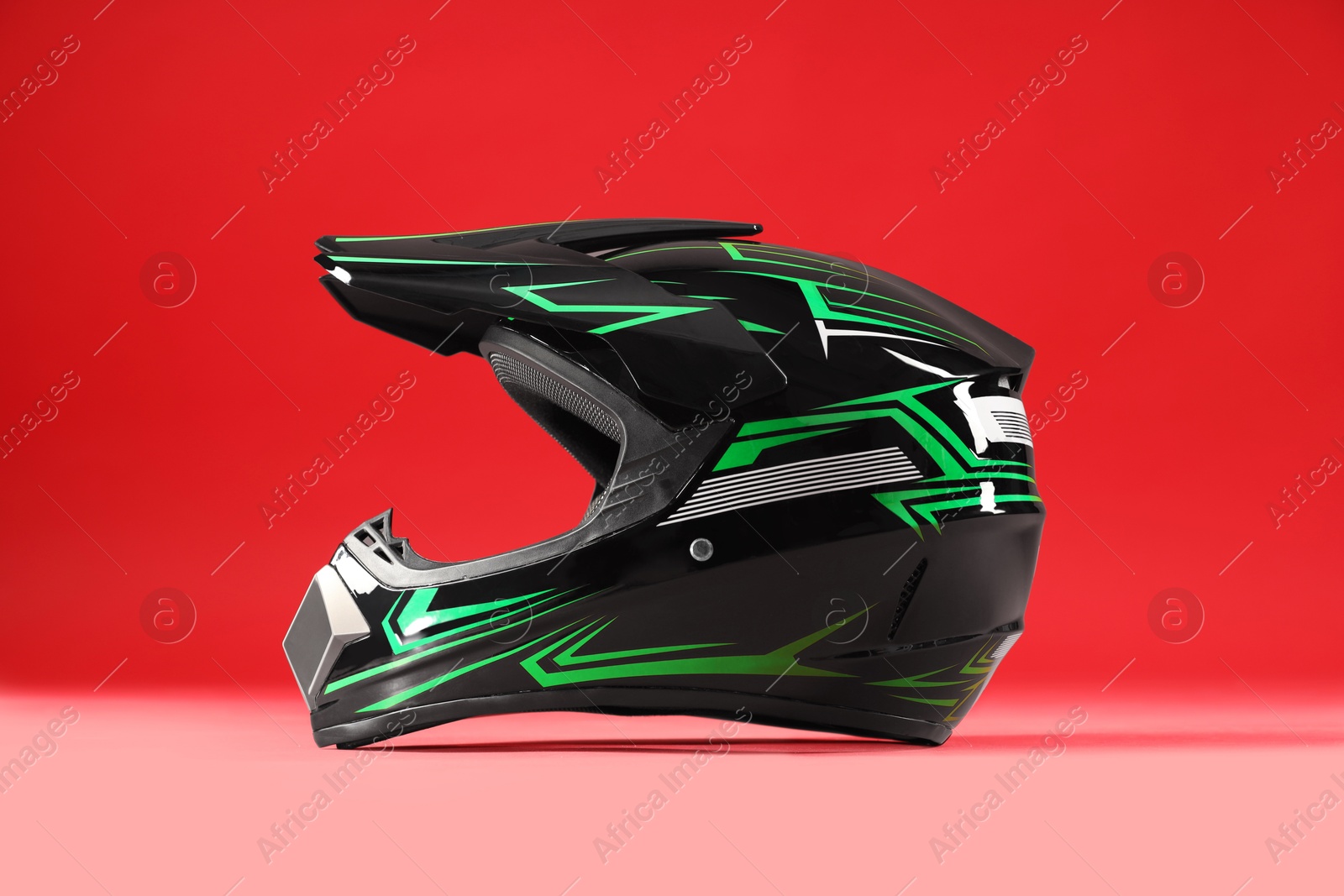 Photo of Modern motorcycle helmet with visor on red background