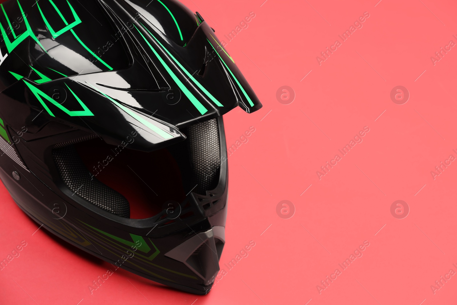 Photo of Modern motorcycle helmet with visor on red background. Space for text