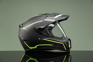 Modern motorcycle helmet with visor on mirror surface against light grey background