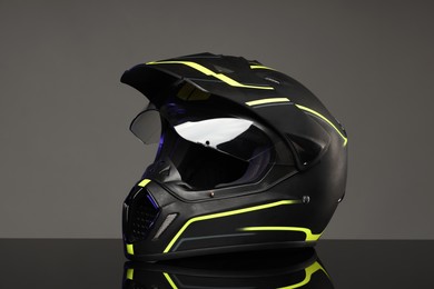 Modern motorcycle helmet with visor on mirror surface against light grey background