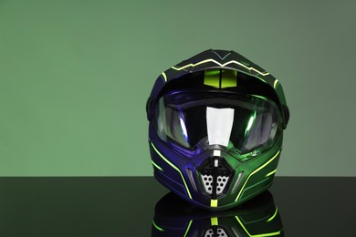 Photo of Modern motorcycle helmet with visor on mirror surface against grey background. Space for text