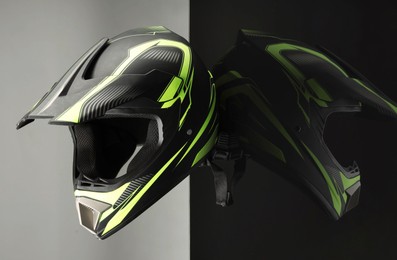 Photo of Modern motorcycle helmet with visor on mirror surface against light grey background