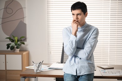 Photo of Embarrassed young man near table in office