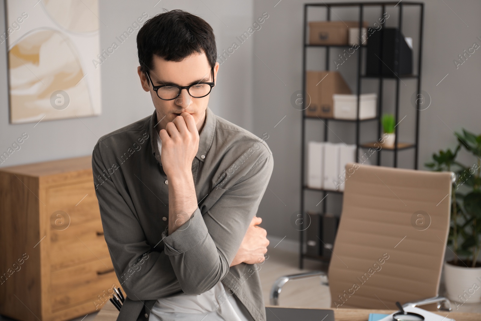 Photo of Embarrassed young man in glasses in office