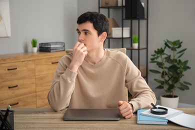 Photo of Embarrassed man at wooden table with laptop in office