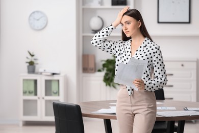 Photo of Embarrassed woman with documents in office, space for text