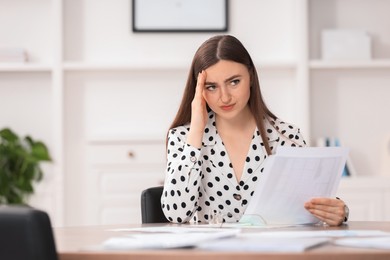 Photo of Embarrassed woman with documents at table in office, space for text