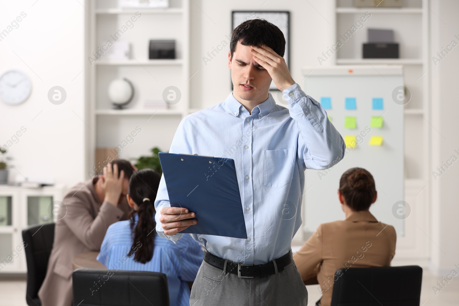 Photo of Man with clipboard feeling embarrassed during business meeting in office