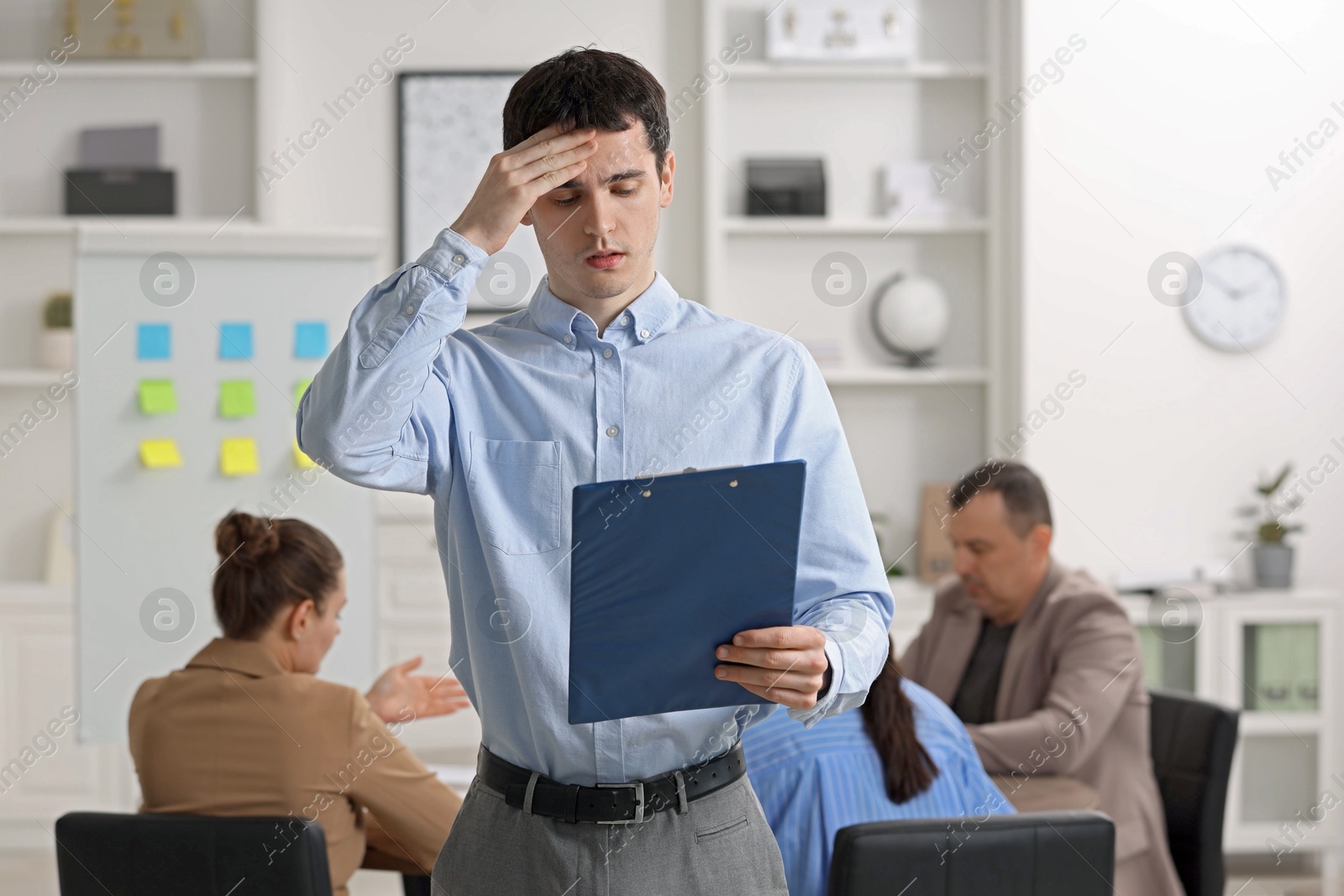 Photo of Man with clipboard feeling embarrassed during business meeting in office