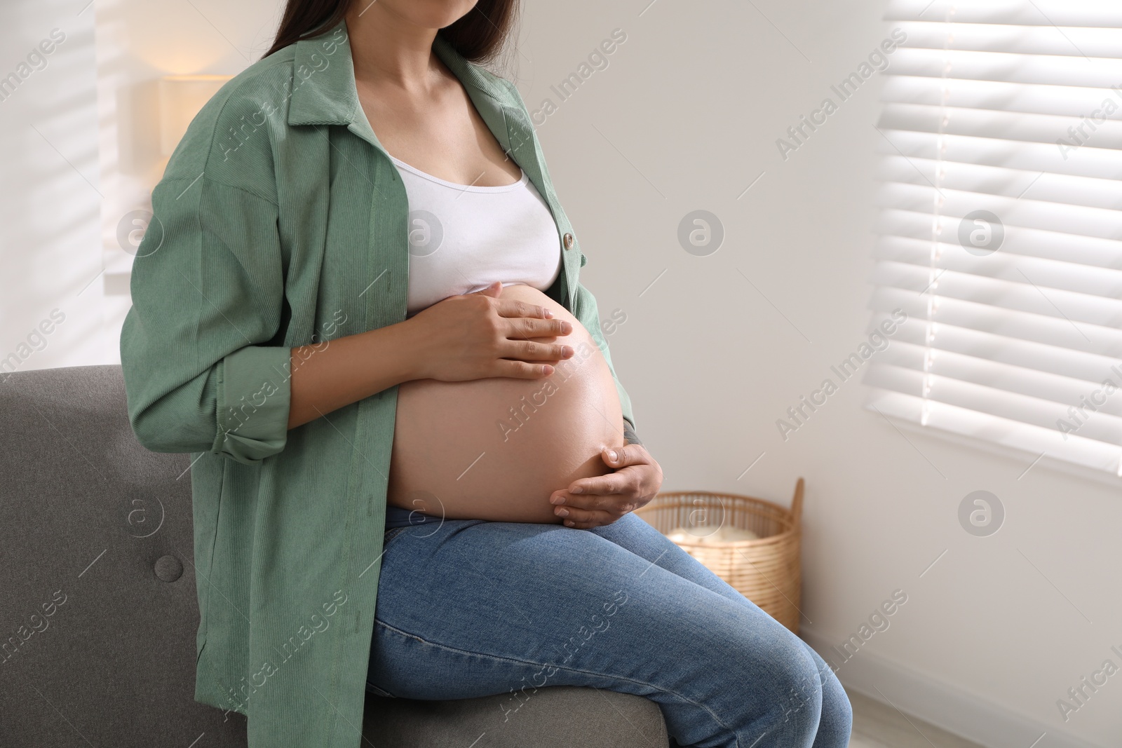 Photo of Pregnant woman sitting on sofa at home, closeup