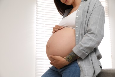 Photo of Pregnant woman at home, closeup. Space for text