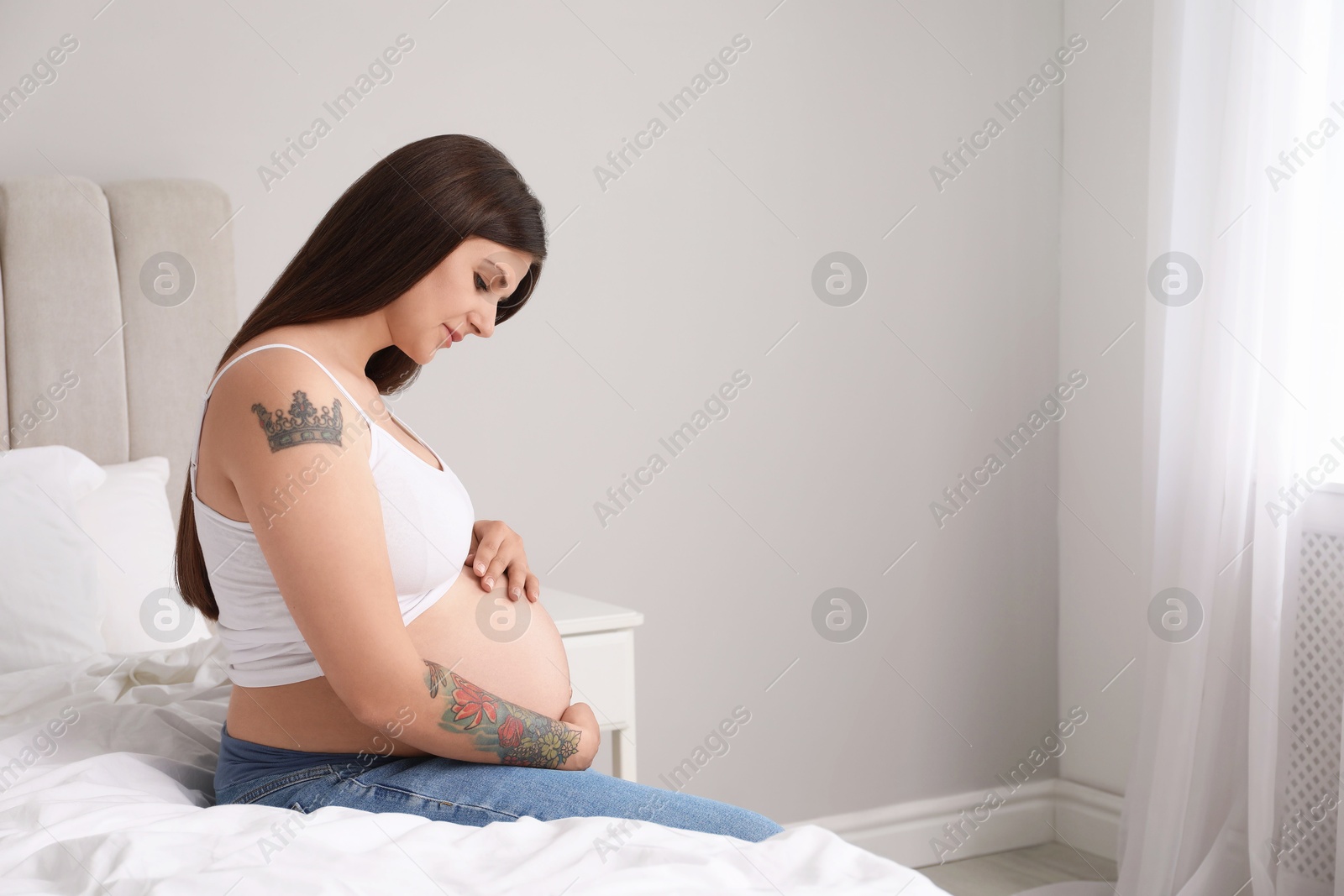 Photo of Beautiful pregnant woman on bed at home, space for text