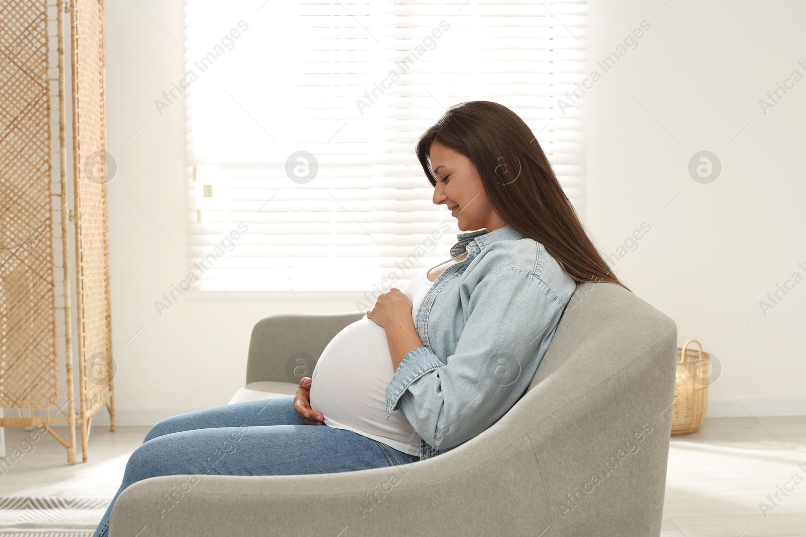 Photo of Beautiful pregnant woman sitting on sofa at home