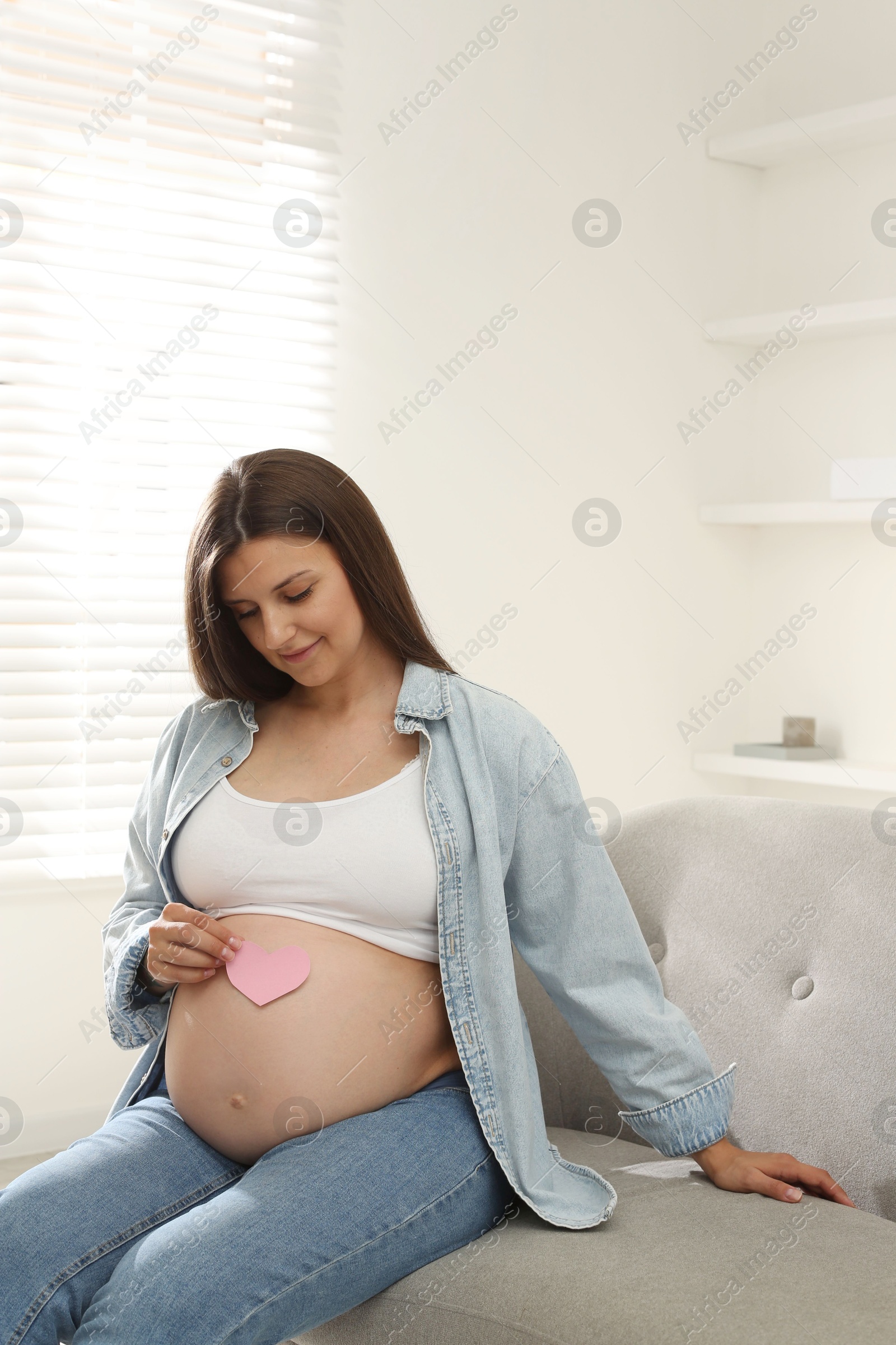 Photo of Beautiful pregnant woman sitting on sofa at home