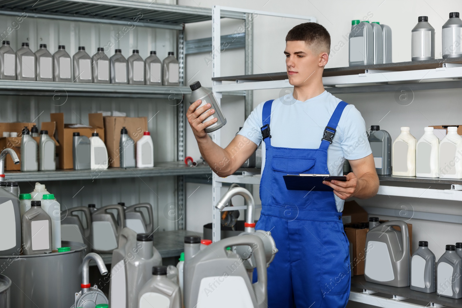 Photo of Young man with clipboard and different car products in auto store