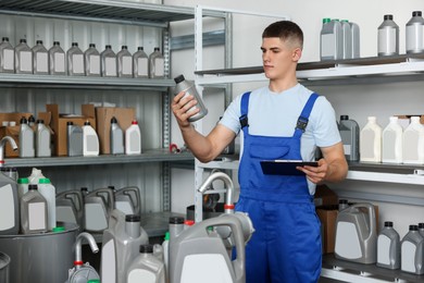 Young man with clipboard and different car products in auto store