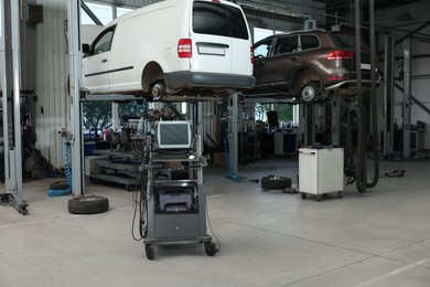 Photo of Automobile repair shop with lifted broken cars and diagnostic tools