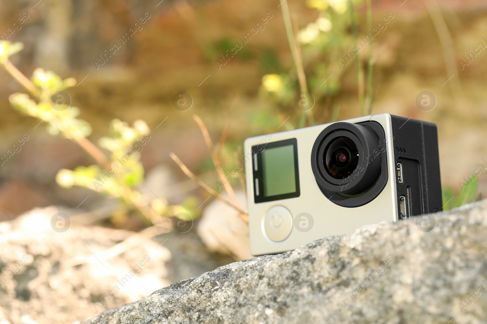 Photo of Modern action camera on stone, space for text