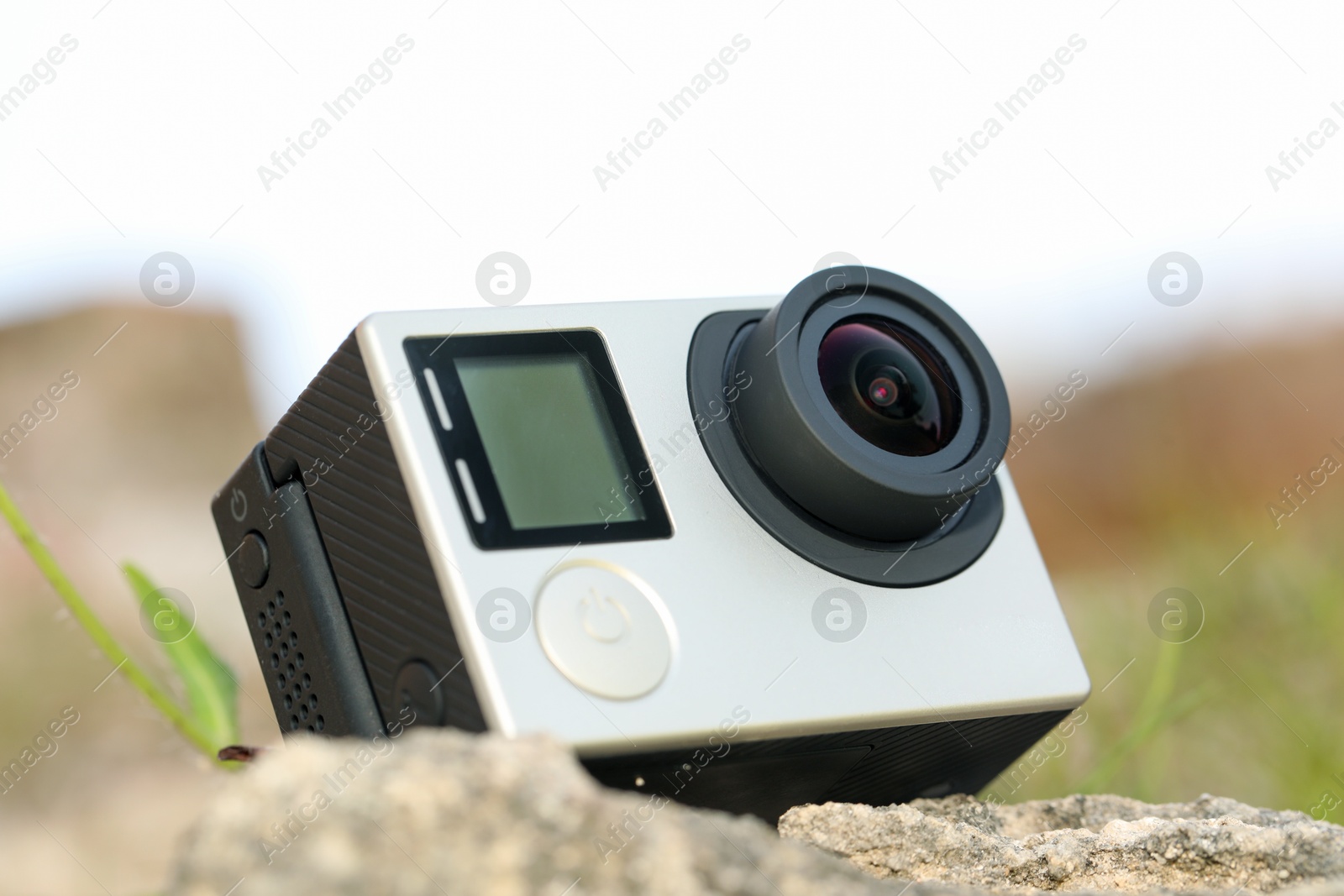 Photo of Modern action camera on stone outdoors, closeup