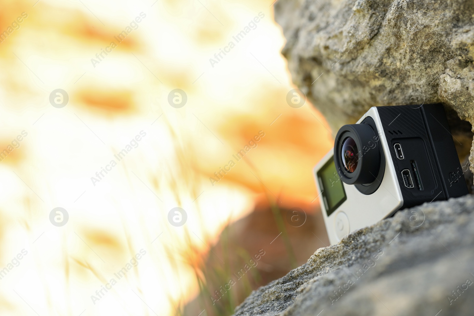 Photo of Modern action camera on stone, low angle view. Space for text