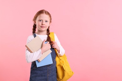 Photo of Cute little girl with books and backpack on pink background. Space for text