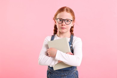 Photo of Cute little girl with book on pink background