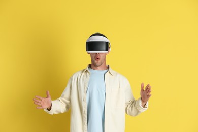 Photo of Surprised man using virtual reality headset on yellow background