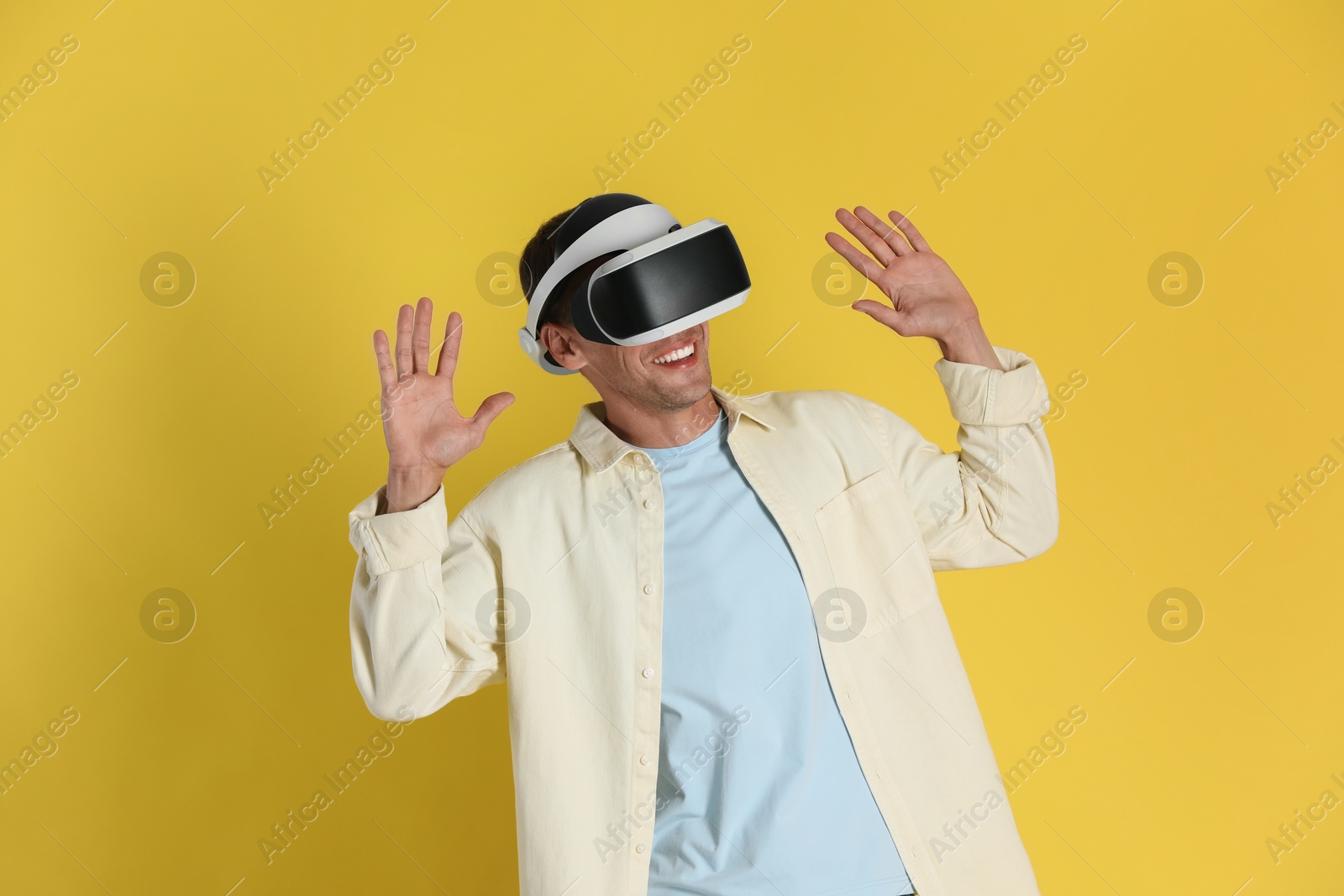 Photo of Smiling man using virtual reality headset on yellow background