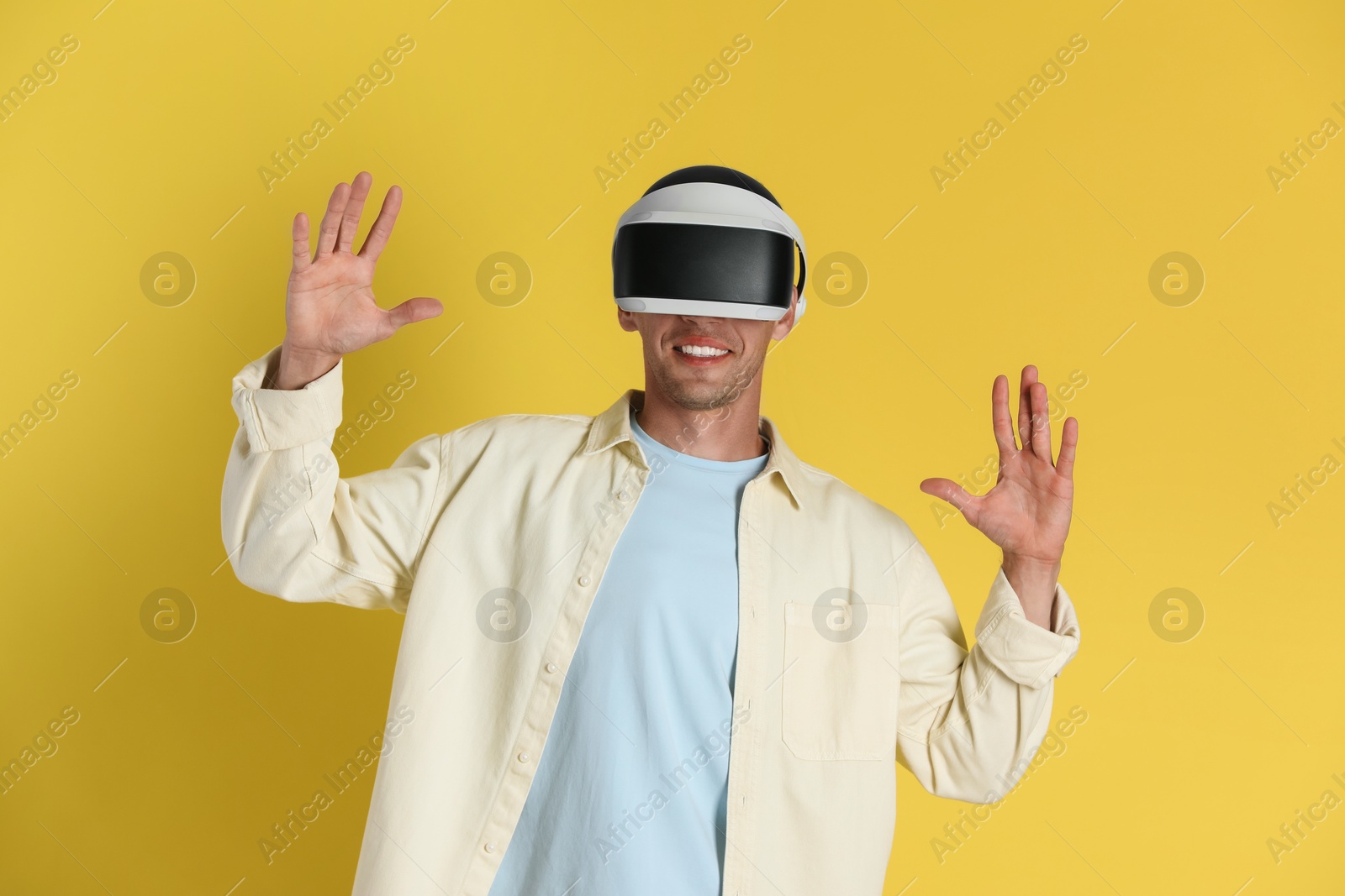 Photo of Smiling man using virtual reality headset on yellow background